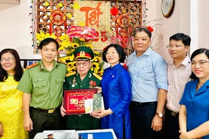 Bí thư Quận ủy quận 5 Huỳnh Ngọc Nữ Phương Hồng cùng thành viên đoàn thăm, tặng quà ông Trần Thăng Phúc. Ảnh: CHÍ THẠCH