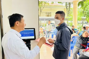 Do lượng người dân đến làm thủ tục đất đai đông, Chi nhánh Văn phòng Đăng ký đất đai Châu Đức phải cử người hỗ trợ bấm số. Ảnh: QUANG VŨ