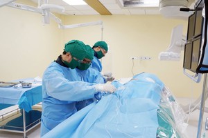 Doctors perform the operation on the elderly woman to palce stent (Photo: SGGP)