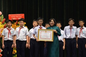 Than Thi Thu ( in green Ao Dai), head of the Ho Chi Minh City Party Committee's Commission for Propaganda and Education, hands certificates of merit to a good student (Photo: SGGP)