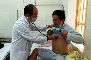 A medical worker is examining an adult suffering measles in Hanoi (Photo: SGGP)