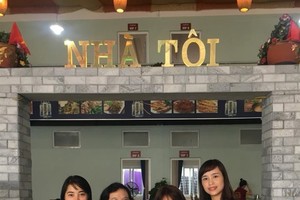 My Home: Trang stands with customers outside her restaurant.— Photo courtesy of Nguyen Thi Dai Trang