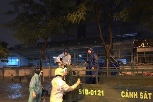 Traffic police help people to move through deep inundated streets (Photo: SGGP)