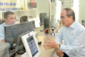 HCMC Party Leader Nguyen Thien Nhan (R) talks to a public servant in District 12 about residents’ satisfaction with administrative procedures (Photo: SGGP)