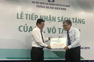 Deputy chairman of Committee for Overseas Vietnamese Vo Thanh Chat (L) gives the books to HCMCUT representative (Photo: SGGP)