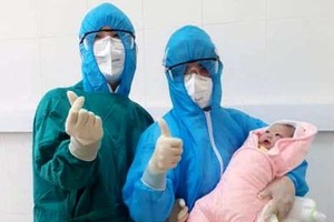 Medical workers carry the newborn baby in the quarantine ward (Photo: SGGP)