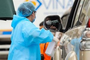 A medical worker sprays a hospital visitor with sanitiser. — Photo nld.com.vn