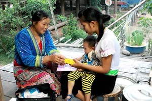 A village-based midwife gives health care guidance to a mother in Muong Nhe district, the northern mountainous province of Dien Bien. (Photo: VNA)