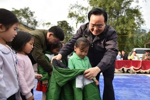 Minister Phung Xuan Nha is delivering warm clothes to poor children. (Photo: SGGP)