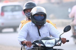 Motorbike riders in Hà Nội have to wear masks on a dusty highway section through Cau Dien - Nhon (Photo: VNA)