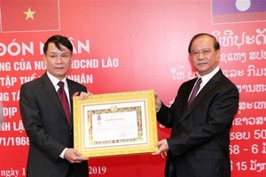 VNA General Director Nguyen Duc Loi (L) receives the second-class Isala (Freedom) Order bestowed by the Lao State. (Photo: VNA)