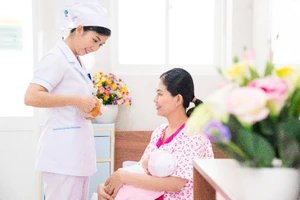 Nữ hộ sinh tư vấn cho sản phụ về tư thế cho con bú.