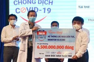 Ông Lê Thế Chữ, Tổng biên tập báo Tuổi Trẻ TPHCM trao bảng tượng trưng món quà bạn đọc báo gửi tới Bệnh viện Bệnh Nhiệt đới TPHCM Ảnh: DUYÊN PHAN