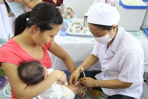 Nhân viên y tế tiêm vaccine cho trẻ