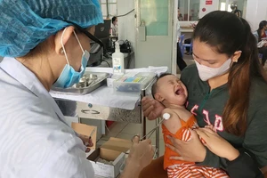 Nhân viên y tế tiêm vaccine sởi cho trẻ