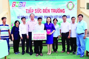 Ông Lưu Hoàng Tân - Chủ tịch, Giám đốc Công ty TNHH MTV Xổ số kiến thiết tỉnh Đồng Tháp (thứ 7 từ phải sang) trao học bổng cho em Vinh