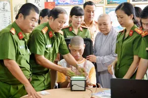 Cán bộ Đội Quản lý hành chính về trật tự xã hội Công an quận 12 làm thủ tục lấy vân tay cho em Phạm Minh Quân bị bệnh bại não tại cơ sở Mái ấm Minh Tâm