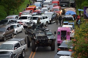 圖為一輛裝甲運兵車和逃離馬拉維市的居民車輛。（圖源：Getty Images）