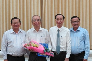 市人委會常務副主席黎清廉向市勞動與榮軍社會廳副廳長阮文熙(左二)送鮮花並頒發退休《決定》。（圖源：市黨部新聞網）