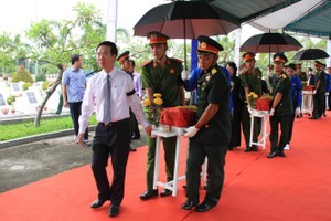 中央宣教部長武文賞(左)陪同烈士親友、烈屬抬起一具棺槨，移送烈士骸骨到安葬的地方。（圖源：蘇芳）