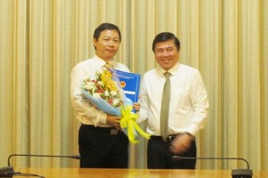 市人委會主席阮成鋒(右)向原市國立大學副校長楊英德頒授委任市新聞與傳播廳長職務《決定》。（圖源：喬峰）