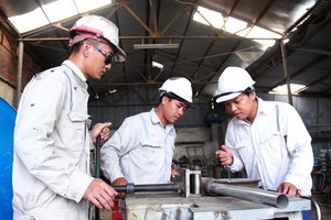 鄧維盛（右）與同事在調整圓管折彎機上。