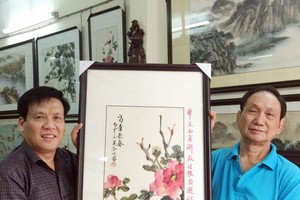 阮玉英主編（左）接受張漢明書畫家贈送畫作。