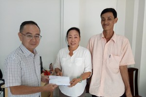 圖1：本報編委兼編輯部主任范興亦把建屋經費轉交予第八郡紅十字輔助會會計阮氏理。