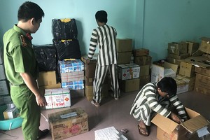 不久前在假藥生產案中被拘捕的疑犯在市公安廳幹部的 監察下點算贓物。