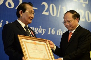 市委常務副書記畢成剛向市教育部 門工會主席阮友雄轉授國家主席的三等 勞動勳章。（圖源：自忠）