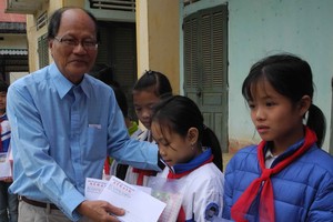 溫陵會館常值副理事長洪世真代表轉交本報贈送的禮物代金予貧困學生。