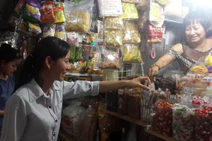 平西市場華人商販向顧客介紹蜜餞。