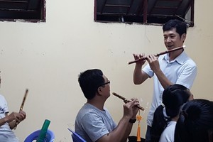 甘偉恒老師在教學生吹簫。