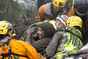 緊急救援人員從坍塌的家裡救出一名渾身裹滿泥土的女子。（圖源：路透社）