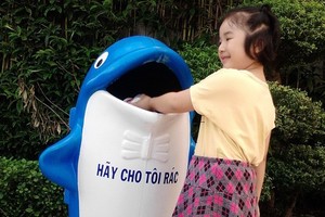 在吃完冰淇淋後，小妹妹親手把紙杯扔進垃圾桶去。