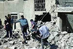 敘利亞東古塔地區遭轟炸，民眾從瓦礫中抬走一具屍體。（圖源：路透社）