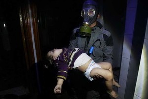 冒險搶救敘利亞平民遭化武攻擊，救援組織「白盔」成員戴上防毒面具，趕赴現場救治。（圖源：AP）