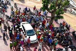 數十人圍繞著汽車上的一對男女，誤認他們倆企圖綁架當地兒童。（圖源：德英）