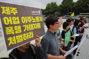 眾人集中在漢城的韓國總統辦事處外面高舉要求懲處某漁船船長涉嫌毒打兩名越南漁民事件的標語牌。（圖源：韓國時報）