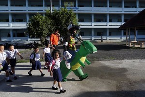 泰國坤西育府交警Tanit扮成恐龍在路上執勤，小朋友們每次上學放學時，看到他都高興極了。（圖源：EPA）