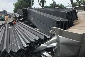 故事現場駕駛室距離集裝箱車體約4米，被上百根鋼條壓住，司機被困在駕駛室內，多束鋼條墜落路上。（圖源：越南快訊）