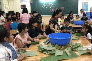 天恩外語中心老師們教小朋友使用蕉葉編織小船、粽子模型。