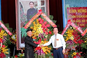 吳策實同志(右)代表越南祖國陣線中央委員會向和好佛教教會中央理事長贈送鮮花祝賀。（圖源：國忠）