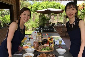 遊客(右)與屋主一同烹煮當地的傳統美食。