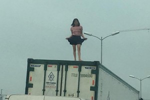 1名精神病婦女爬上集裝箱頂上瘋狂地手舞足蹈大聲叫喊，使眾人深感驚訝。（圖源：Q.B）