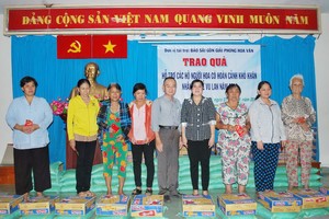 本報編委兼編輯部主任范興(右五)與新富 郡祖國陣線委員會副主席阮氏雪梅(右四)給貧 困戶贈送禮物。