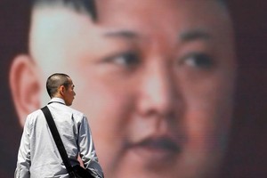 東京街頭，一位路人經過正在播放金正恩講話的大屏幕。（圖源：路透社）