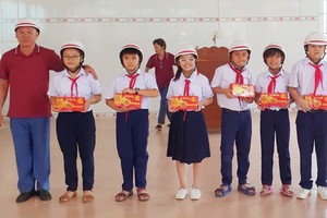 鄭成龍理事長向兒童贈送月餅及安全帽。