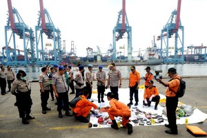 10月30日，在印度尼西亞雅加達戈戎不碌港口，印尼警方與國家搜救局工作人員查看失事客機乘客的個人物品。（圖源：新華網）