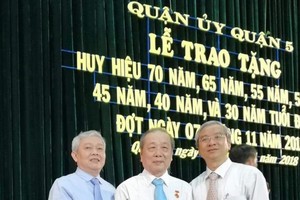 第五郡郡委書記武進仕（左）和郡人委會主席范國輝（右）送花祝賀華人黨員孫盛強。